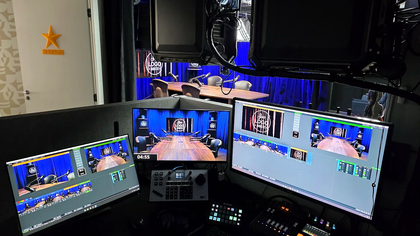 Sala de controle com três monitores exibindo o programa e as câmeras do estúdio